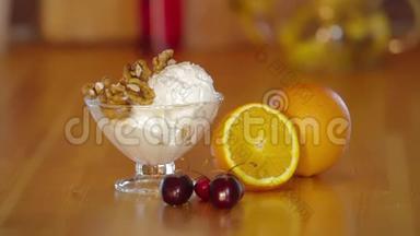 夏日甜点。 玻璃碗里的冰淇淋和核桃。 橘子和樱桃放在木桌上。 冰淇淋的制作